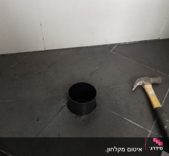 צינור שחור, פטיש ומברג על רצפה אפורה